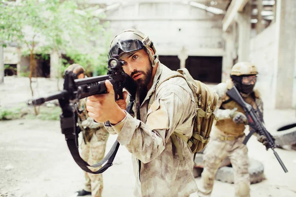 Savaşçı ayakta dışında ve amaç alarak. O tüfeği elinde tutuyor. Diğer iki adam onun arkasında duran ve territoty keşfetmek.