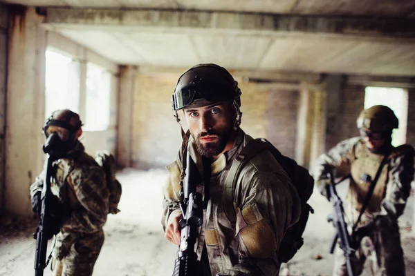 I guerrieri sono in piedi in una stanza vuota. Stanno procedendo con molta attenzione. I ragazzi sul retro indossano maschere speciali. Si proteggono con speciali uniformi e fucili. I ragazzi sono in pericolo. . — Foto Stock