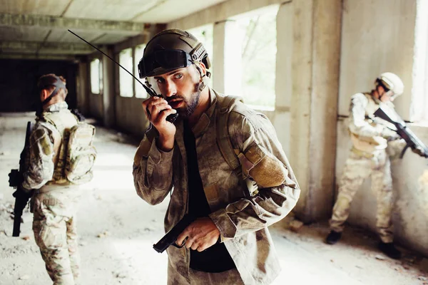 Bir görüntü diğer savaşçılar ile boş odada duran bir adam. O silah tutan ve taşınabilir radyoyla konuşuyordu. Düz görünüyor. Diğer çocuklar bölge koruyor.