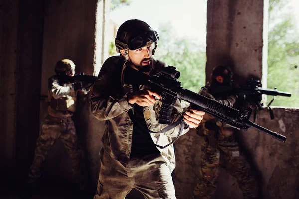 Soldado fuerte y bien construido está de pie con sus oponentes en la habitación oscura y protegiéndolo. están tratando de defenderse. Los chicos se comportan muy bien. . — Foto de Stock