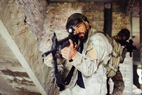 Una foto di un uomo che prende di mira attraverso fucili lenz. Sta guardando dritto in avanti. Il ragazzo e 'serio e concentrato. Altri due ragazzi sono dietro di lui. . — Foto Stock