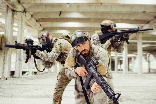 Tre guerrieri stanno posando. Due di loro sta guardando ai lati diversi e prendendo di mira attraverso lenz fucile mentre l'uomo davanti è loooking dritto e tenendo il fucile pure . — Foto Stock