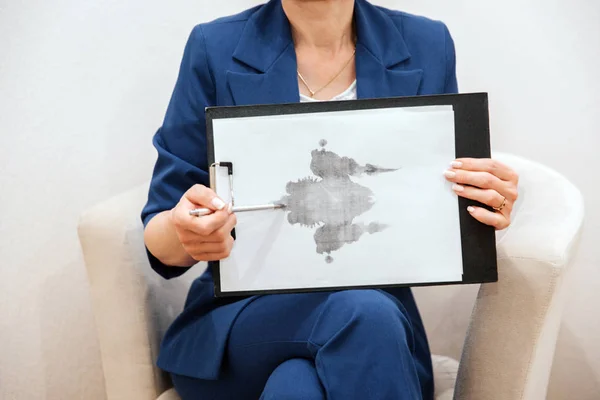 Женщина сидит и держит фотографию. Это ручной рисунок. Он прикреплен к планшету. Женщина указывает ручкой на картинку . — стоковое фото