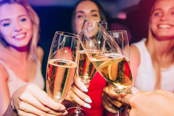 Una foto donde las chicas tintinean con copas de champán. Las chicas las están mirando y sonriendo. Hay dos chicas rubias y una morena . — Foto de Stock