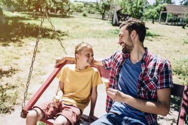 Sakallı adam ve oğlu salıncakta dışarı tüyler ürpertici. Onlar birbirine yakın oturan ve gülümseyerek. Ayrıca onlar-si olmak biraz dondurma elinde.