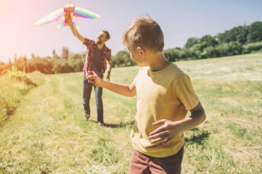 Çalışan ve geriye dönüp baktığımda çocuğun resmini. İş parçacığında uçurtma tutuyor. Babası onu uçurtma gökyüzüne çalıştırmak için yardımcı oluyor.