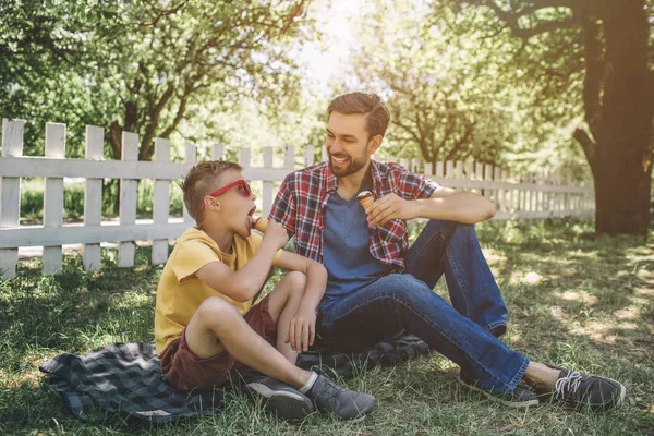 Otra imagen genial de adultos y niños sentados juntos y mirándose entre sí. Están comiendo helado. Niño pequeño lleva gafas . — Foto de Stock