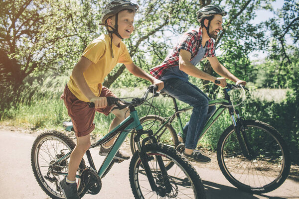 Отец и сын едут на велосипедах. Они едут по маленькой дороге. Каждый из них хочет быть первым на финише
.