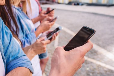 Genç insanlar farklı telefon elinde tutan bir resim. En yakın olan adamın elleri ile karanlık telefon.