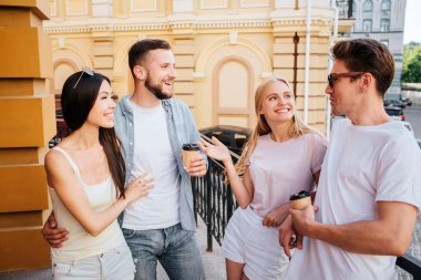 Güzel arkadaşları birlikte birbirlerine önünde duran ve konuşuyor. Sakallı adam f kahve tutarak ve Çinli kız arkadaşı kucaklayan. Sarışın kız gözlüklü adam bakıyor.