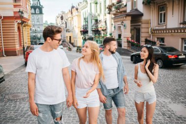 İki çiftler sokakta yürüyor. Gözlük ve sarışın kız adam önünde yürüyor. Onlar birbirine bakarak ve gülümseyerek. Arkasında başka bir çift yürüyüş.