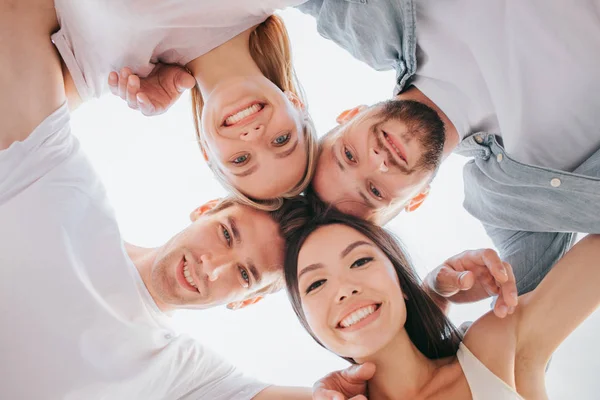 Schönes Bild positiver Teenager, die ihre Köpfe eng aneinander halten und in die Kamera schauen. Sie lächeln. Es sind zwei Jungen und zwei Mädchen. Sie halten sich die Hände auf den Schultern. — Stockfoto