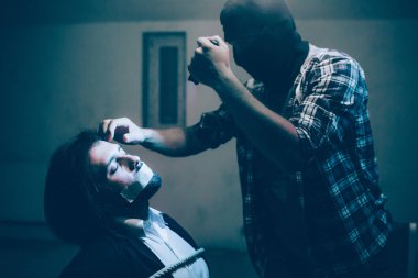 Kaçırılan işadamı sandalyede oturan ve iplerle bağladılar. Gözleri kapalı tutuyor. Katil onun önünde duran ve kurbanını alnına dokunuyor. Ayrıca halen elinde kamera tutuyor.