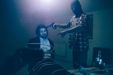 Yorgun ve üzgün kurban sandalyede oturan ve telefon arıyor. Biri adam kaçırma video kaydediyor. Maskeli adam ayakta ve elinde silah kurban kafa yakın. Ayrıca şuna işaret ediyor.