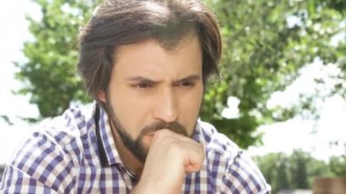 Yakışıklı adam dışında oturan ve ellerini ovuşturarak kapatın. Endişeleniyor. ve dudakları el ile dokunmak. Adam çok üzücü. El ile baş fırçalıyor. Adam aşağı ve düz arıyor. Pişman.