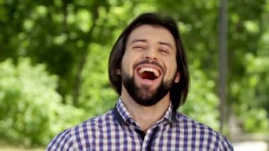 Neşeli adam kameraya bakıyor ve gülümsüyor. Yüksek sesle laughint o. Adam yukarı ve düz kamera üzerinde birkaç kez arıyor. Sonra o adam yüzünü elleri ile bir süre koruyor.