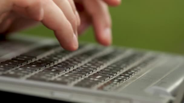 Крупним планом пальці чоловіка натискають кнопки на клавіатурі. Він друкує його. Він тримає ноутбук на ногах. Чоловік сидить надворі в парку . — стокове відео