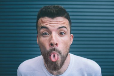 Kamera ve hsowing dilini bakarak sakallı adam portresi. Çocuklar kaşları yukarı yetiştirilir. Çizgili ve siyah arka plan üzerinde izole.