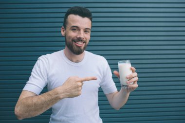 Pozitif adam ayakta ve poz. O süt Holding'in ve üzerinde işaret. Adam gülümseyerek ve kameraya bakıyor. Çizgili ve mavi arka plan izole.