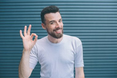 Neşeli ve mutlu bir adam ile parmak shwoing ok sembolüdür. O kameraya bakıyor ve gülümsüyor. Çizgili ve mavi arka plan izole.