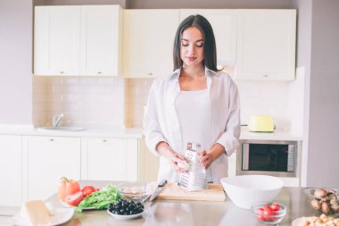 Güzel kız donatmak anlamına gelir ve rende yakın haşlanmış yumurta tutar. O aşağı görünüyor. Sakin ama konsantre kızdır.