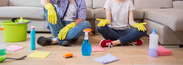 Cut view of man and woman sitting on the floor and resting. She is meditating. Man and woman has their legs crossed. There are cleaning equipment all over the floor. — Stock Photo, Image