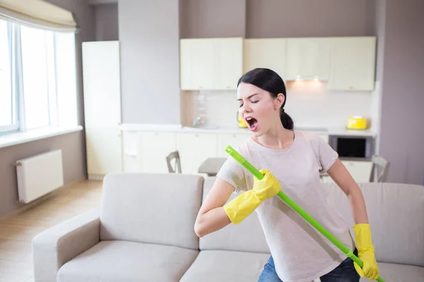 Grappige foto van brunette groene stok in handen houden. Ze doet alsof dat het microfoon is. Meisje zingt erin. Ze is erg creatief en grappig. — Stockfoto