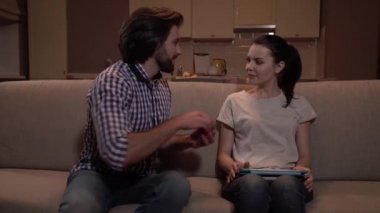 Kız kanepede oturan ve tablet ile çalışma. Adam ona gelir, koltukta oturur ve küçük bir kutu ile halka açık. O bir teklif yaptı. Mutlu bir kızdır. O adam benimsemiş.