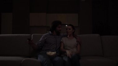 Güzel çift karanlıkta oturuyor ve seyretmek Tv. Guy kase patlamış mısır diz vardır. Kız uzaktan kumanda olsun istiyor. Adam ama gülümsüyor vermek istemiyor. Kız üzgün ama seyretmek devam süsü.