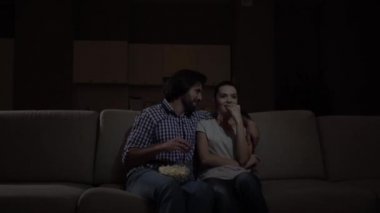 Erkek ve kadın sittign birlikte ve izlerken film vardır. Onlar yemek patlamış mısır ve gülüyor. Patlamış mısır dizlerinin üzerinde bir kase yaşamalı. Gülüyor duramazsın. Kız puan ileri.