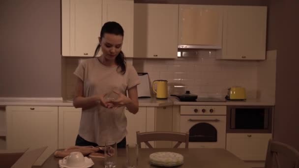 La chica está empacando dos vasos en caja y cerrándola. El tipo viene a la cocina, toma la caja y se va. Se miran y sonríen. Pareja es feliz . — Vídeos de Stock