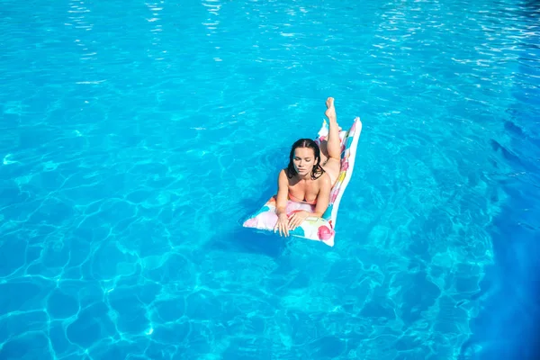 Nice and well-built girl is lying on air mattress and getting some tan from sun. She is serious and concentrated. Girl has some rest. — Stock Photo, Image