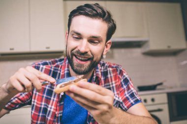 Sakallı adam masada oturur ve kızarmış ekmek bıçağı ile tutar. O biraz tereyağı koyar. Adam aşağı görünüyor. O aç ama memnun.