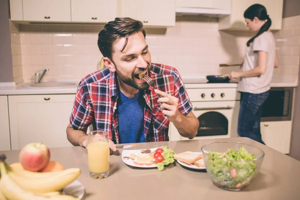 Aç adam masada oturan ve yemek çatalı onda ısırma. Adamın gözleri kapalı tutuyor. Kız soba anlamına gelir ve aşçılar gıda. — Stok fotoğraf