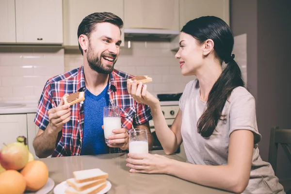Güzel bir çift masada oturur ve birbirlerine göz resmi. Çikolatalı hamur ile tost tutuyorlar. Ayrıca bardak süt ellerinde vardır. İnsanlar mutlu görünüyorsun. — Stok fotoğraf