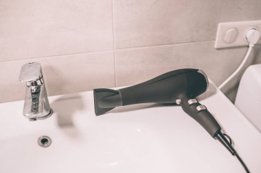 Saç kurutma makinesi lavabo üzerinde resmi. Bağlı yuva için. Aygıt banyoda yalan söylüyor.