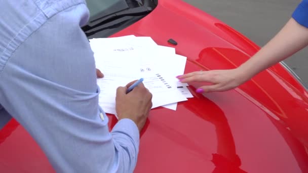 En bild av människor står vid bilen och underteckna papper. Flickan pekar på plats för att logga. Killen gör som. De upprepa det två gånger. — Stockvideo