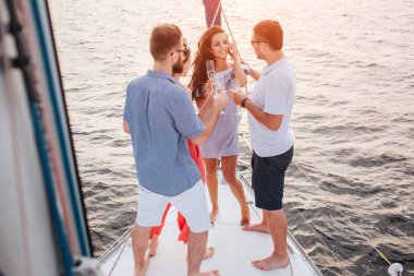 Esmer arayan üç kişi resmini. Onlar konuş onunla. O gülümseme ve göz. İnsanlar yat yay stand. Güneş.