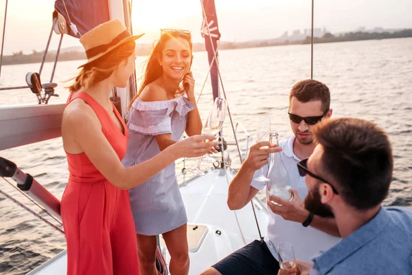 Vier Menschen stehen sich gegenüber und jubeln. Ein Mann hält eine Flasche Champagner in der Hand und betrachtet sie. Ein anderes Volk lächelt. Sie sind glücklich. — Stockfoto