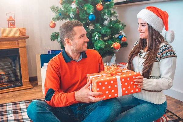 Beuatiflu pareja sentarse juntos en manta y mirarse el uno al otro. Tienen un regalo y sonríen. La gente es feliz . — Foto de Stock