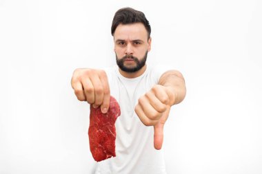 Kötü et parçası elinde tutan genç adamın resmi. Büyük başparmak aşağı gösterir. Adam kızgın ve üzgündüm. Kameraya bakıyor. Beyaz arka plan üzerinde izole.