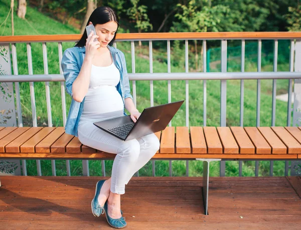 Portretul unui păr negru fericit și o femeie însărcinată mândră într-un oraș în fundal. Modelul feminin funcționează pe computer — Fotografie, imagine de stoc