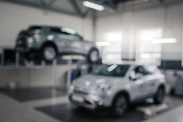 Imagen borrosa de dos coches grises en el salón. Vehículo a la izquierda en la plataforma. Brillan y brillan . — Foto de Stock