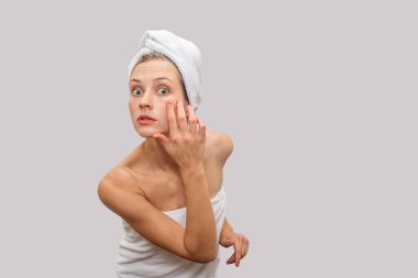 Güzel çilli genç kadın anlamına gelir ve kamera daha yakın görünüyor. Yanak üzerinde bir el tutar. Onun saç ve vücut beyaz havlu ile kaplıdır. Gri arka plan üzerinde izole.