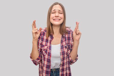 Neşeli genç model parmak çarpı işareti ve gözleri kapalı tutar. O dua ve dilek. Konsantre modelidir. Gri arka plan üzerinde izole.