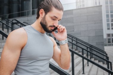 İyi durumda genç adam aşağı yürür. Telefonla konuşuyor. Yoğun biri. Aşağıya bakar. Genç adam handband taraftan sahiptir.