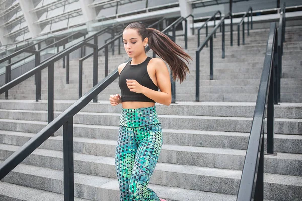 Imagen de atleta mujer salta en escalones. Ella mira hacia abajo. La joven está concentrada. Lleva un bonito uniforme deportivo. . —  Fotos de Stock