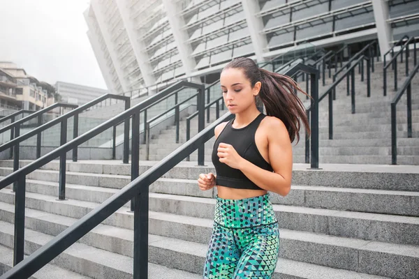 Poziome portret buil No i piękny model jogging kroki. Ona jest poważne i skoncentrowany. Młoda kobieta noszenia czarny i zielony jednolite. — Zdjęcie stockowe