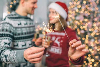 Genç adam ve kadın birbirlerini önünde stand ve Bengal ışık tutun. Onun ışığı pırıl pırıl. Onu sopa yanmıyor. Bardak şampanya tutuyorlar.