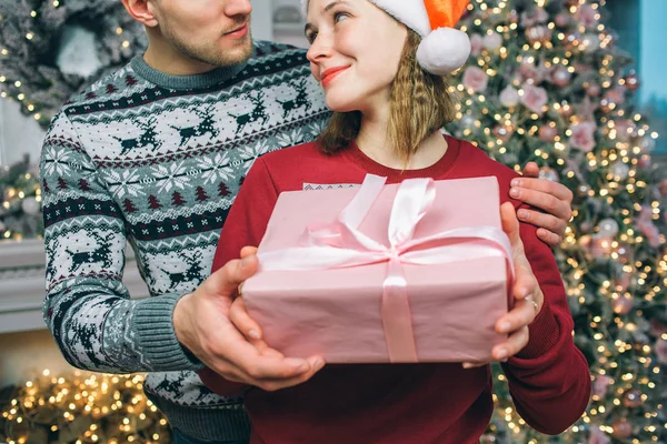 Schönes und nettes Paar stehen zusammen und schauen einander an. sie lächeln. Die Menschen halten zusammen. hinter ihnen liegt der Weihnachtsbaum. — Stockfoto